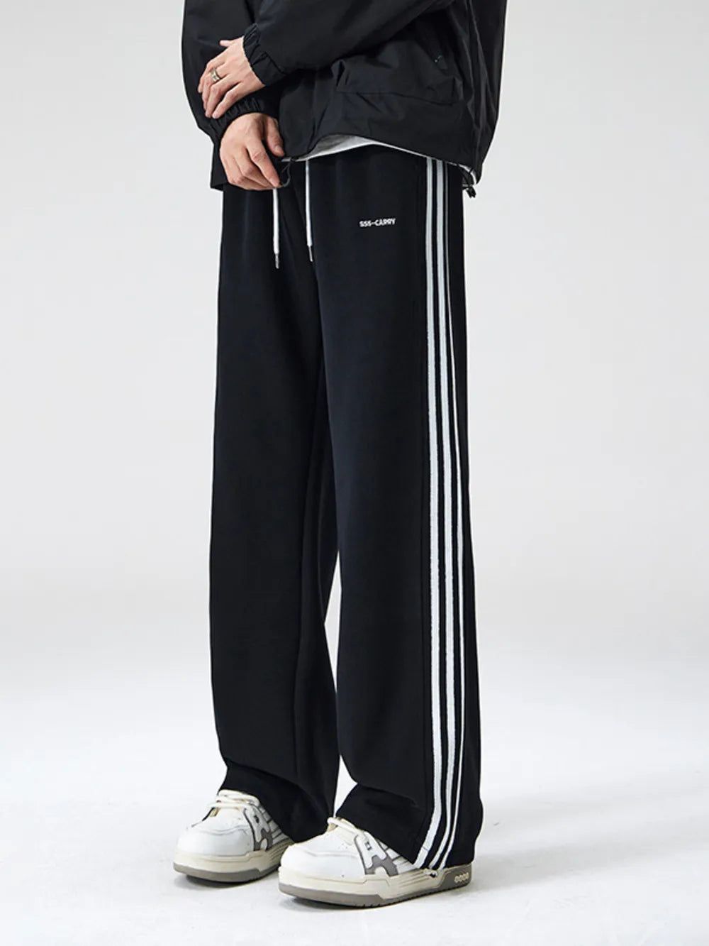 Black wide-leg sweatpants with white side stripes and drawstring waist.