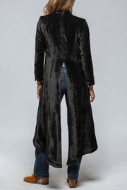 Black velvet duster coat with dramatic split back detail, long sleeves, and a flowing hem.