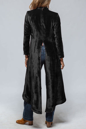 Black velvet duster coat with dramatic split back detail, long sleeves, and a flowing hem.