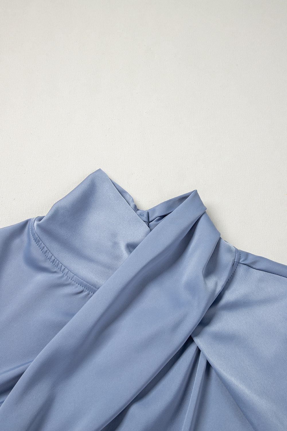 Dusty blue blouse with draped neckline and bell sleeves.