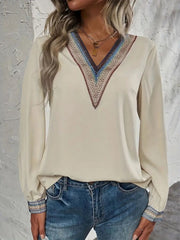 Beige V-neck blouse with colorful embroidered trim on neckline and cuffs.