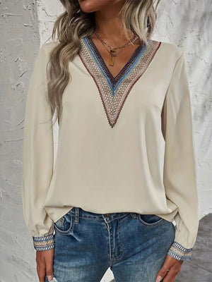 Beige V-neck blouse with colorful embroidered trim on neckline and cuffs.