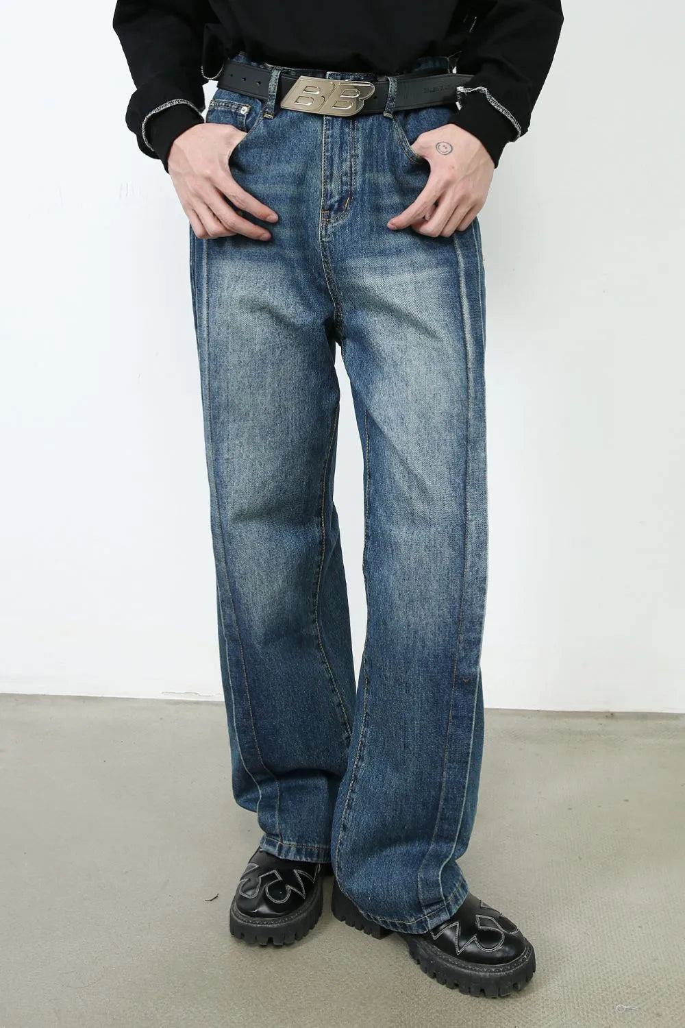 Medium wash denim jeans with vertical seams and wide legs.