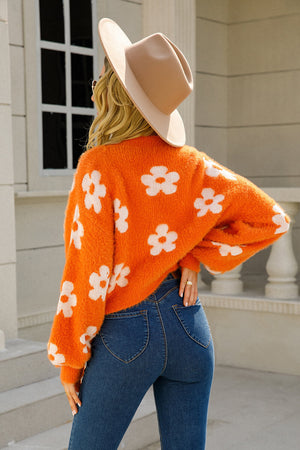 Orange fuzzy cropped cardigan with white floral pattern, long sleeves, and relaxed fit.