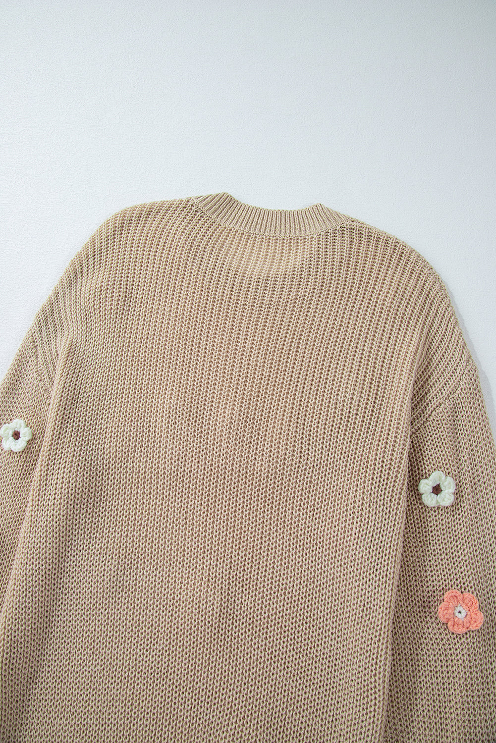 Khaki knit sweater with embroidered floral details on the sleeves.