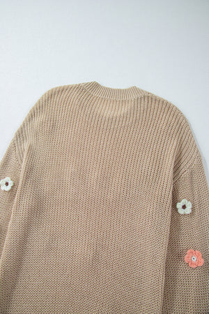 Khaki knit sweater with embroidered floral details on the sleeves.