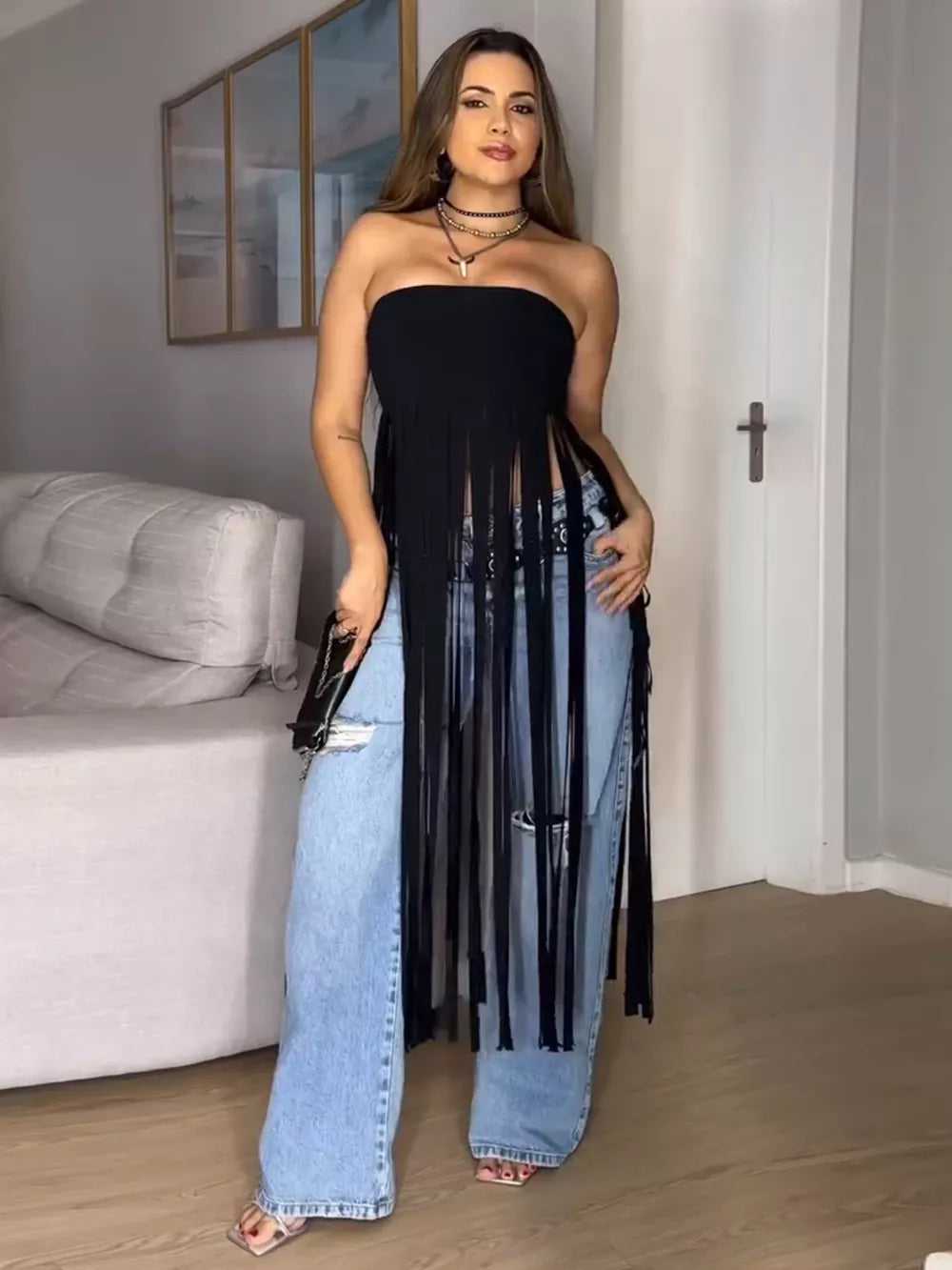 Black bohemian tube top with fringe trim, styled with ripped jeans.