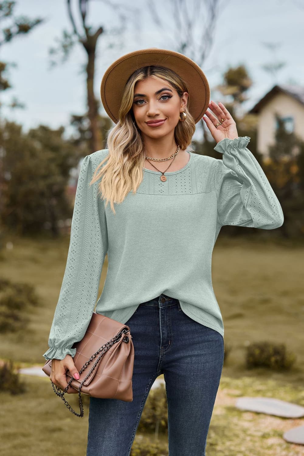 Sage waffle knit blouse with perforated details and ruffled cuffs.