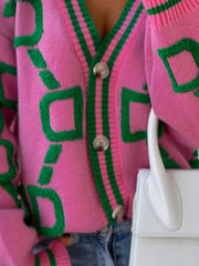 Hot pink acrylic cardigan with green geometric pattern and striped trim.