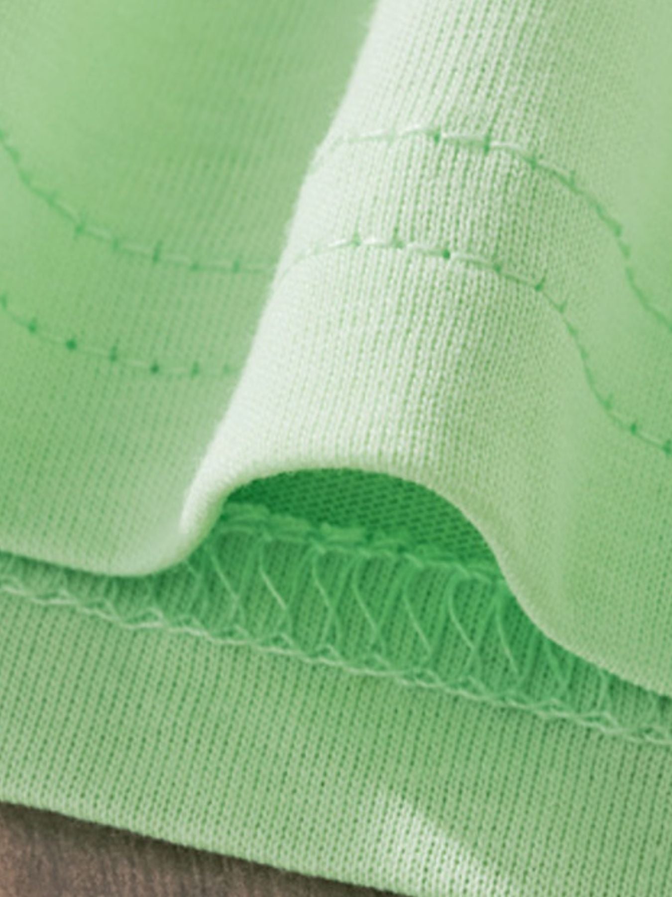 Children's light green cotton tee detail showing stitching and fabric texture.