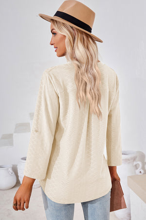 Cream textured henley shirt with roll-tab sleeves and a curved hem.