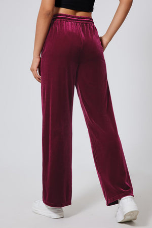 Burgundy velvet palazzo lounge trousers with a drawstring waist and wide leg.