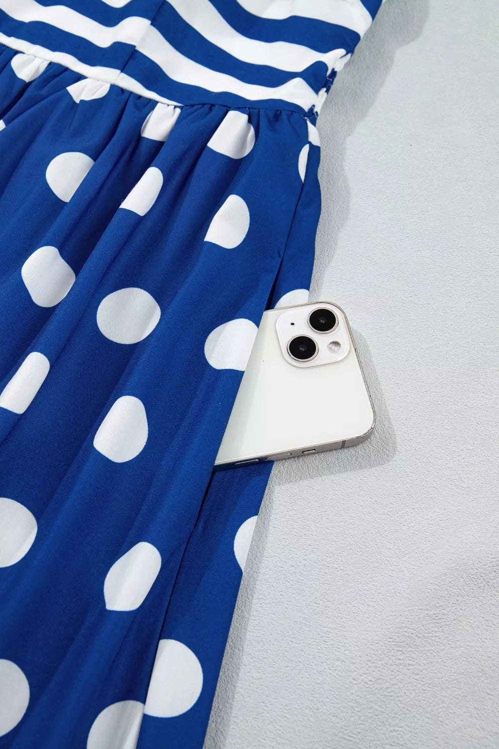 Maxi swim dress with blue and white polka dots and stripes, featuring a pocket holding a phone.