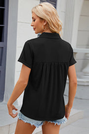 Black polo top with short cuffed sleeves and gathered yoke detail.