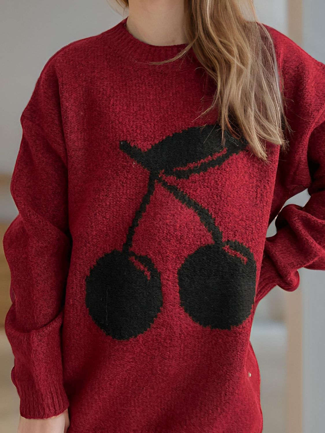 Burgundy knit sweater with black cherry motif, crew neck, long sleeves.