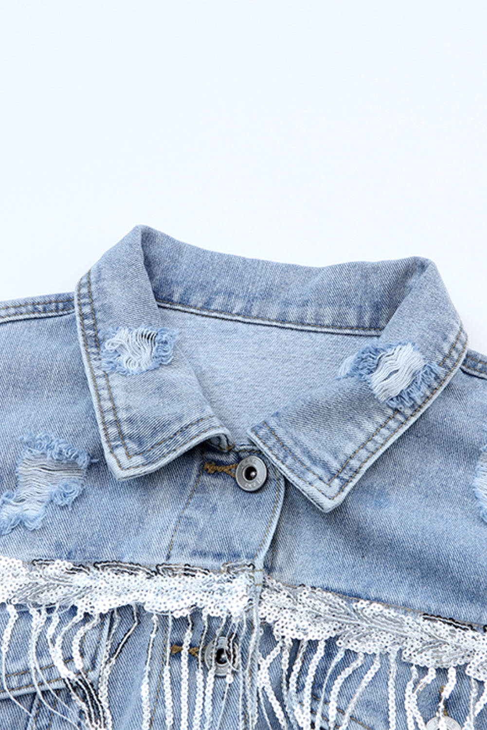 Medium wash denim trucker jacket with distressed details and sequin fringe trim.