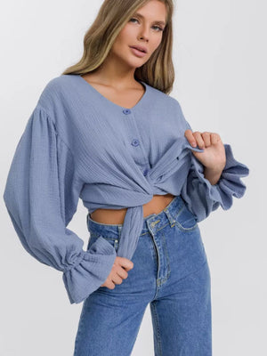Light blue textured blouse with puff sleeves, ruffled cuffs, and a tie front.
