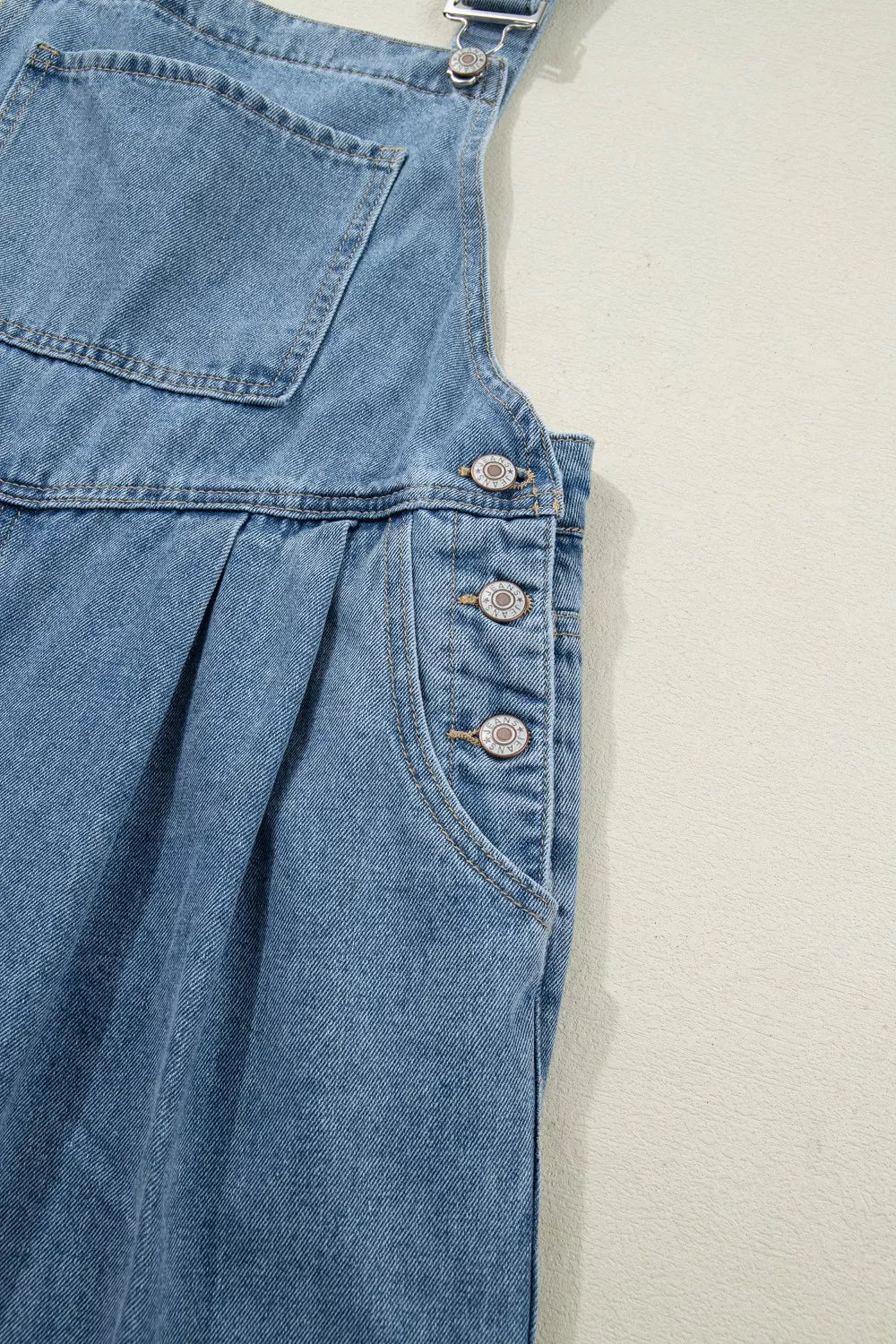 Denim wide-leg jumpsuit with button details and pleats.