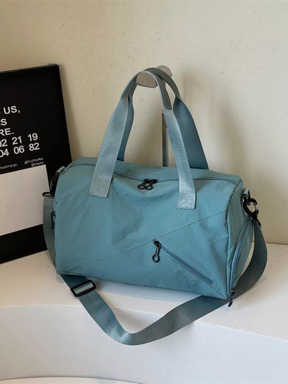 Blue nylon duffel bag with multiple zippered pockets and adjustable shoulder strap.