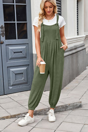Olive green corduroy overalls with barrel legs and tie straps, worn with a white tee.