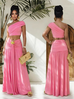 Pink one-shoulder ruched crop top and maxi skirt set with gold accent detail.