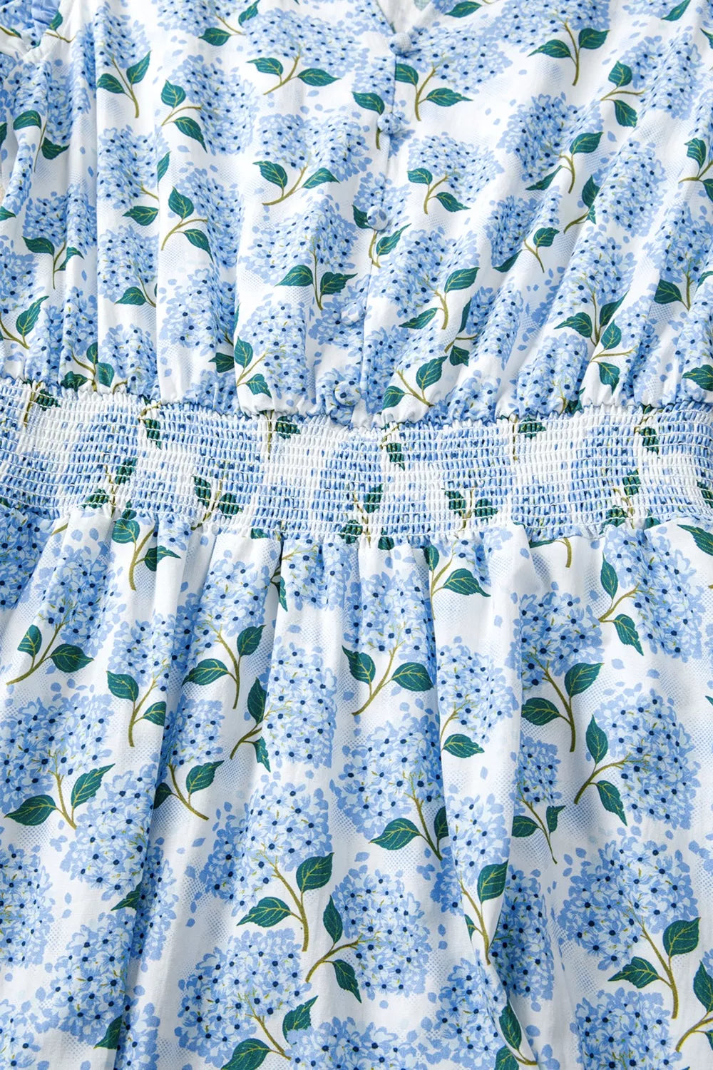 Midi dress with blue hydrangea print, smocked waist, and flutter sleeves.