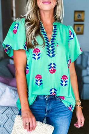 Embroidered floral v-neck blouse with flutter sleeves in light green with pink and blue floral print.