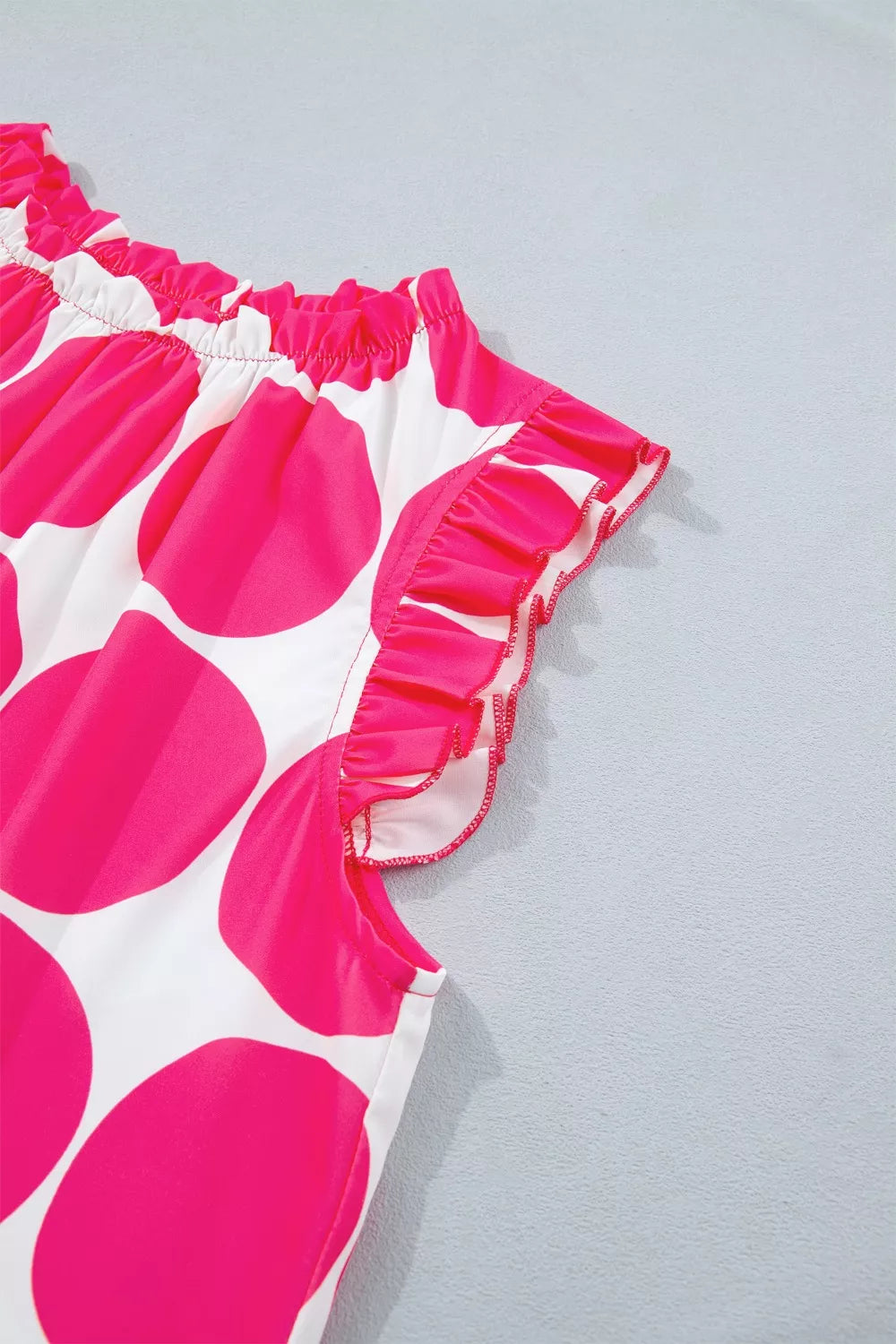 Polyester tank top with pink polka dots and ruffled trim.