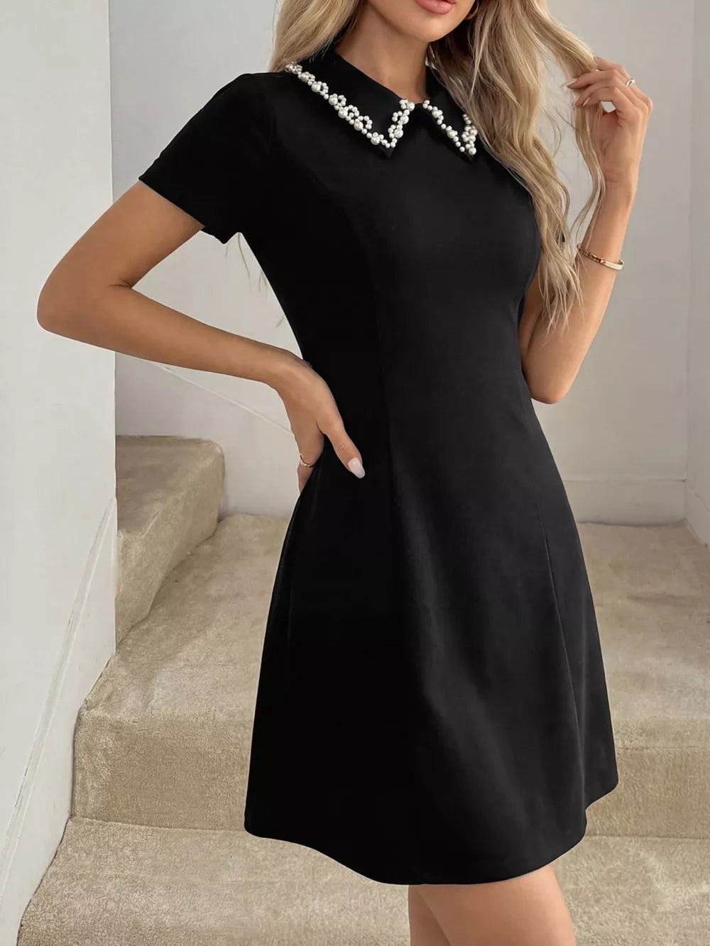 Black A-line mini dress with short sleeves and a pearl-beaded collar.