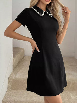 Black A-line mini dress with short sleeves and a pearl-beaded collar.