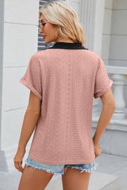 Blush pink perforated polo top with black collar and cuffed short sleeves.