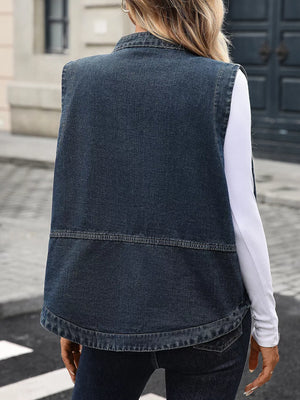 Washed black denim vest with band collar and curved hem, styled over a white long-sleeve top.