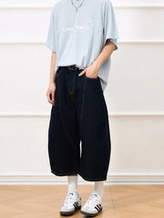 Dark navy cotton denim shorts with a cropped, balloon cut and visible stitching.