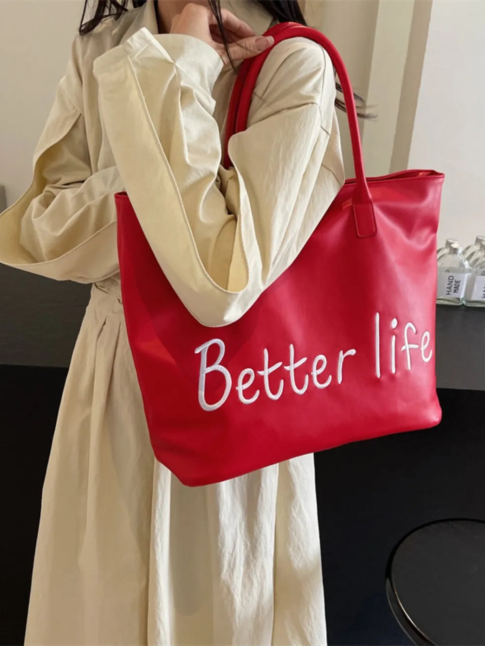 Scarlet tote bag with white Better Life embroidery and red straps.