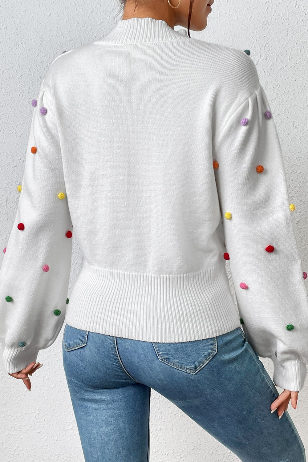 White blouson knit sweater with colorful pom-pom details and balloon sleeves.