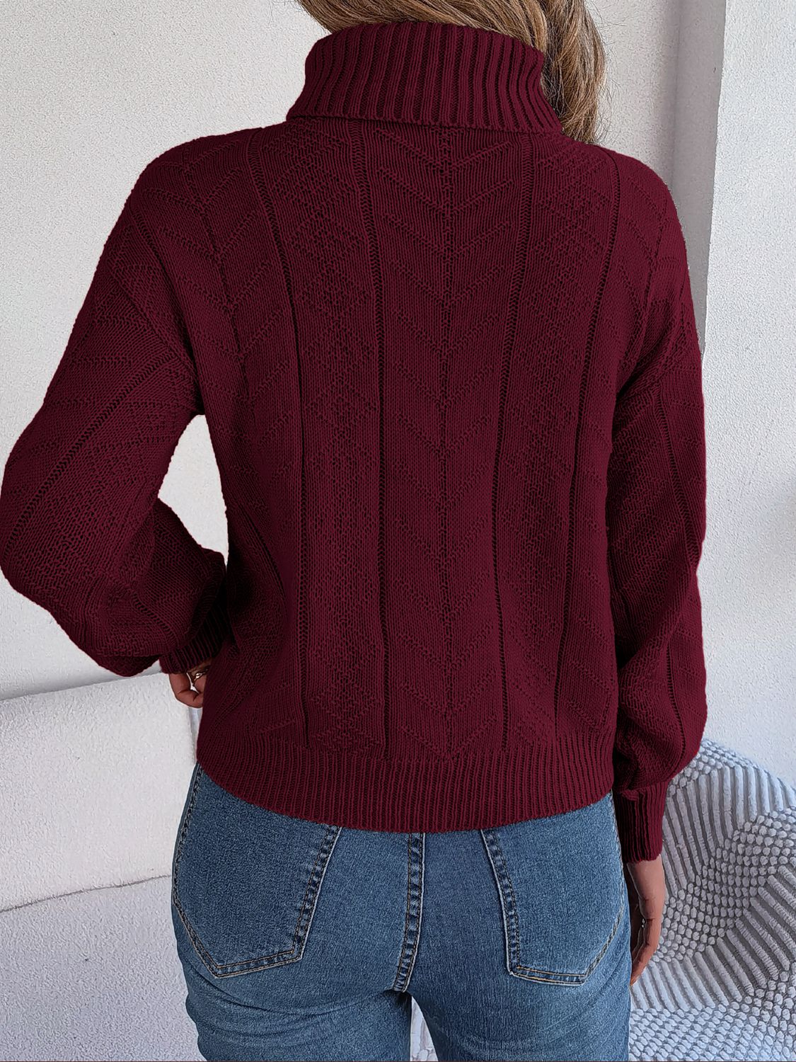 Burgundy cable knit turtleneck sweater with drop shoulder and textured pattern.