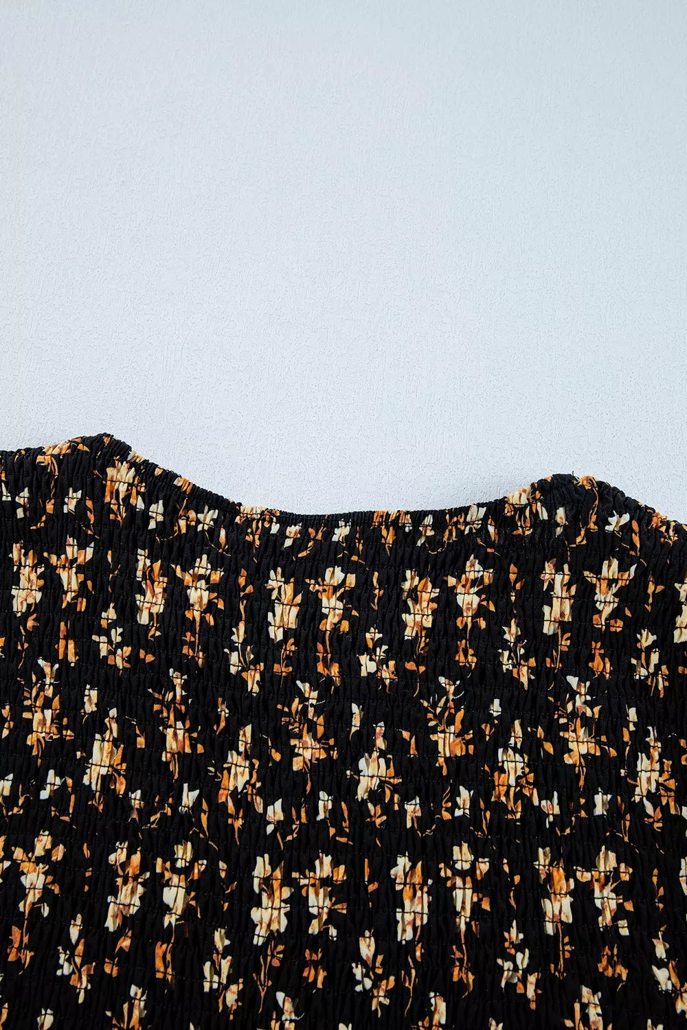 Black floral smocked blouse with a square neckline and long sleeves.
