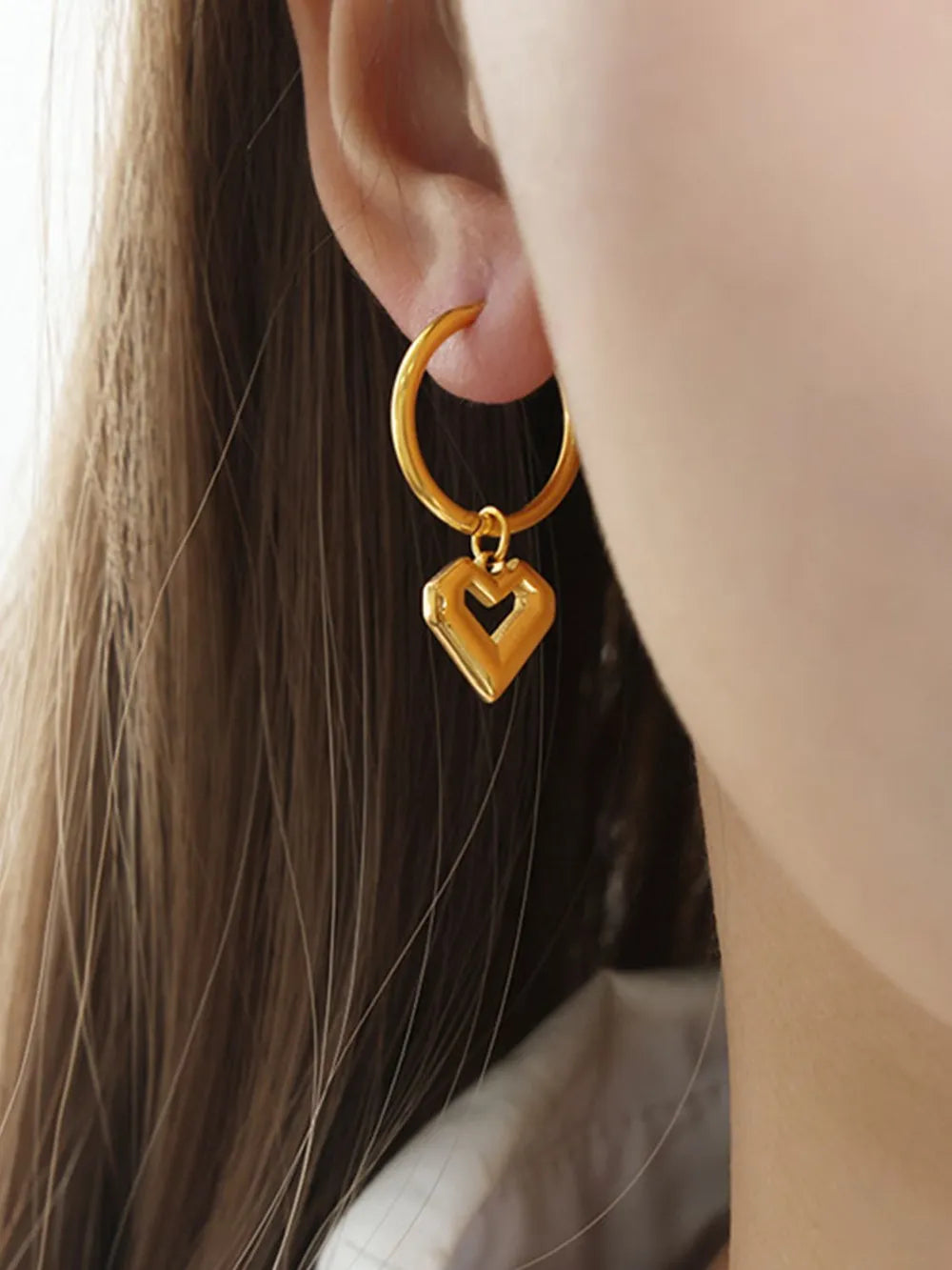 Gold hoop earrings with geometric heart charms