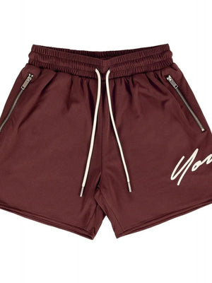 Burgundy jogger shorts with drawstring, zip pockets, and white script logo detail.