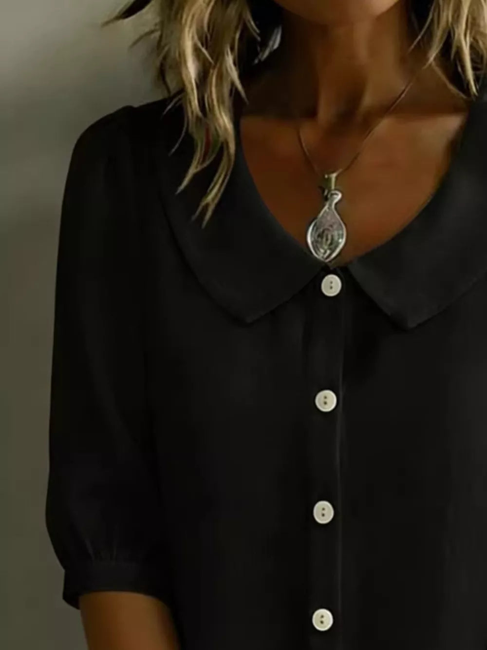 Black puff sleeve shirt with Peter Pan collar and white buttons, styled with a necklace.