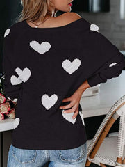 Black raglan knit sweater with white heart motif, crew neck, long sleeves.