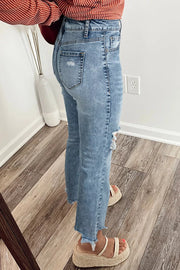 Distressed light wash denim flare jeans with open knees and frayed hem.