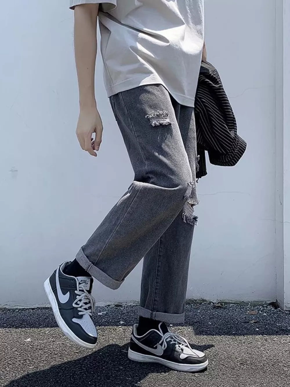 Distressed relaxed fit men's jeans in dark gray with cuffed hems.