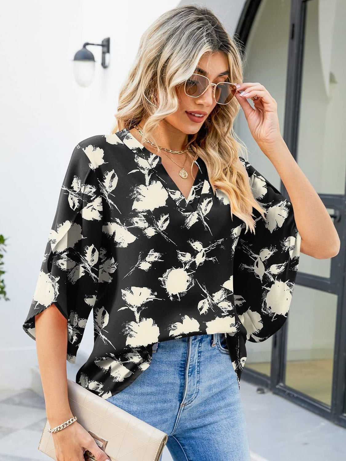 Black floral print blouse with v-neck and flutter sleeves, made of 100% polyester.