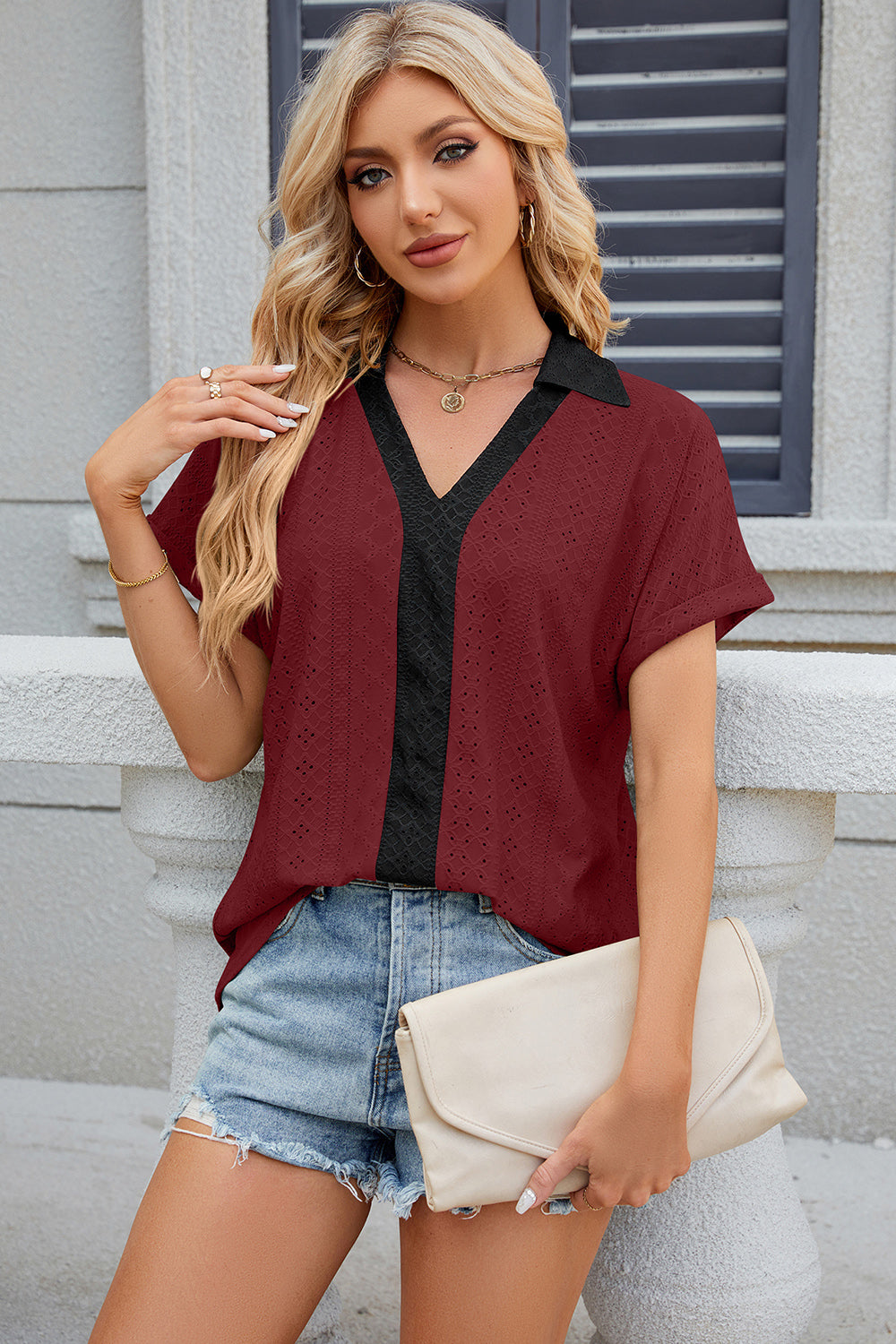 Burgundy perforated polo top with black V-neck detail and short sleeves.