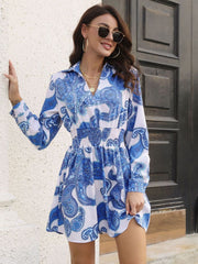 Cobalt blue paisley print shirred waist mini dress with long sleeves and a collared neckline.