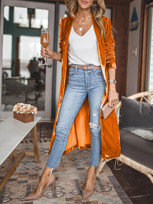 Tangerine velvet duster coat with fluid silhouette, open front, long sleeves, worn with jeans.