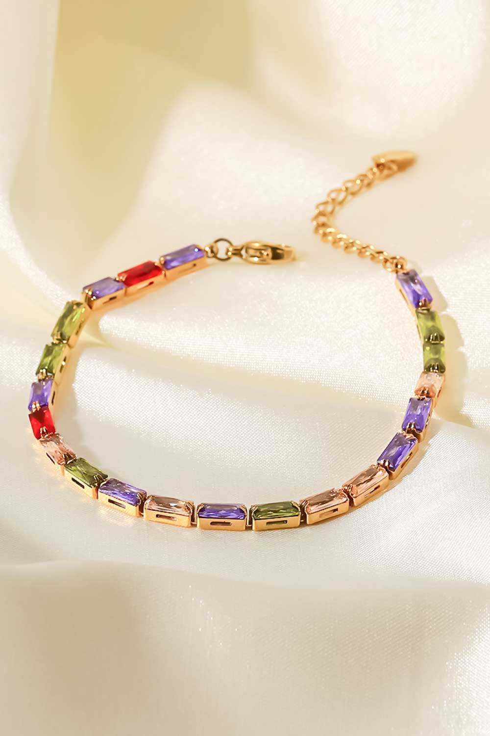 Gold chain bracelet with multi-colored baguette crystals and a clasp closure.