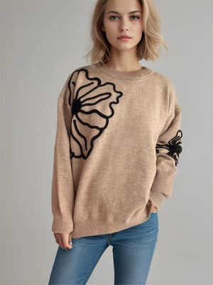 Tan knit sweater with black floral embroidery on the chest and sleeve.