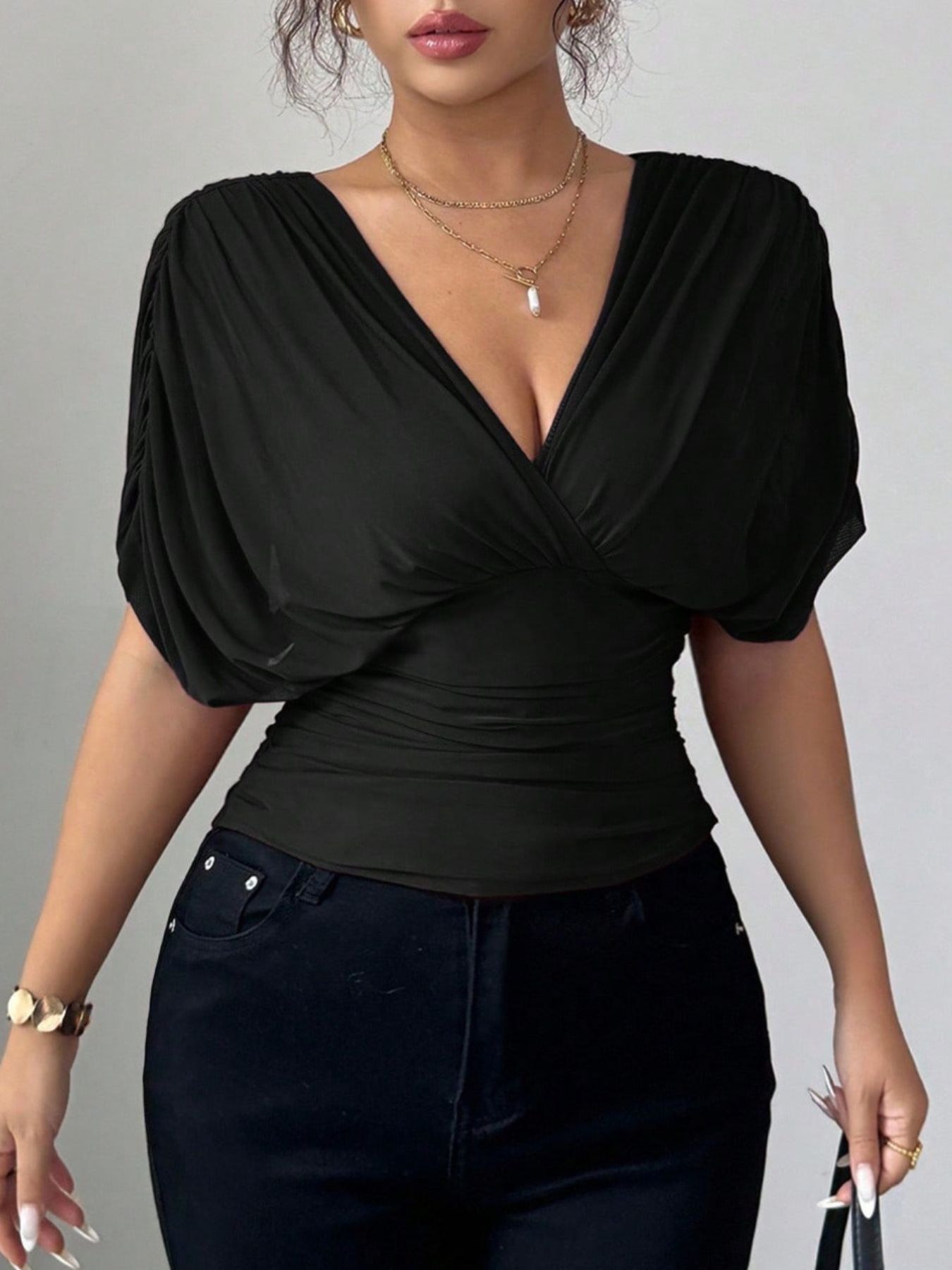 Black ruched surplice dolman sleeve top with a deep V-neckline.